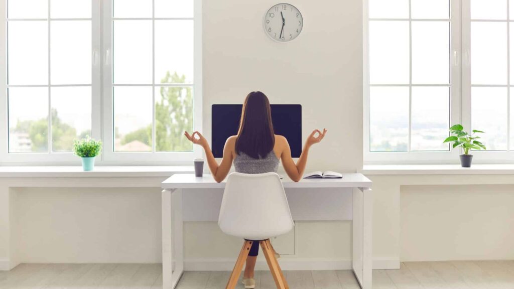 Naine istmas arvuti taga seljaga meie suunas, käed zen asendis