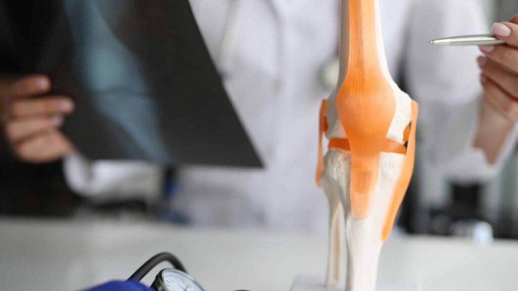 Arst selgitab põlveliigest, osutades pastakaga liigesele