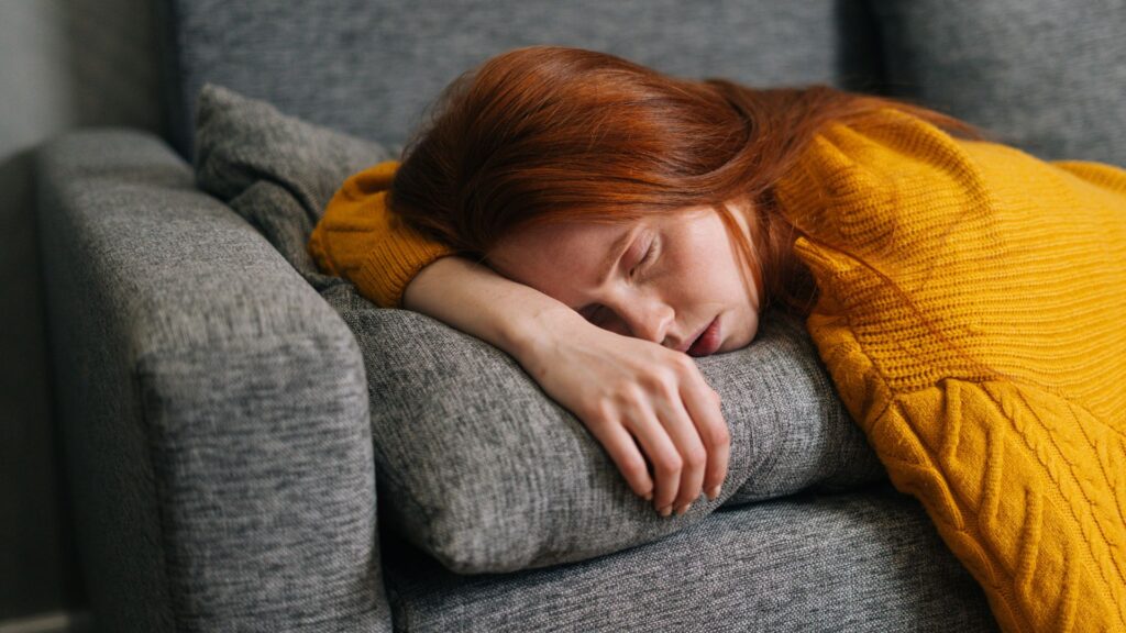 Punapäine naine magab diivanil