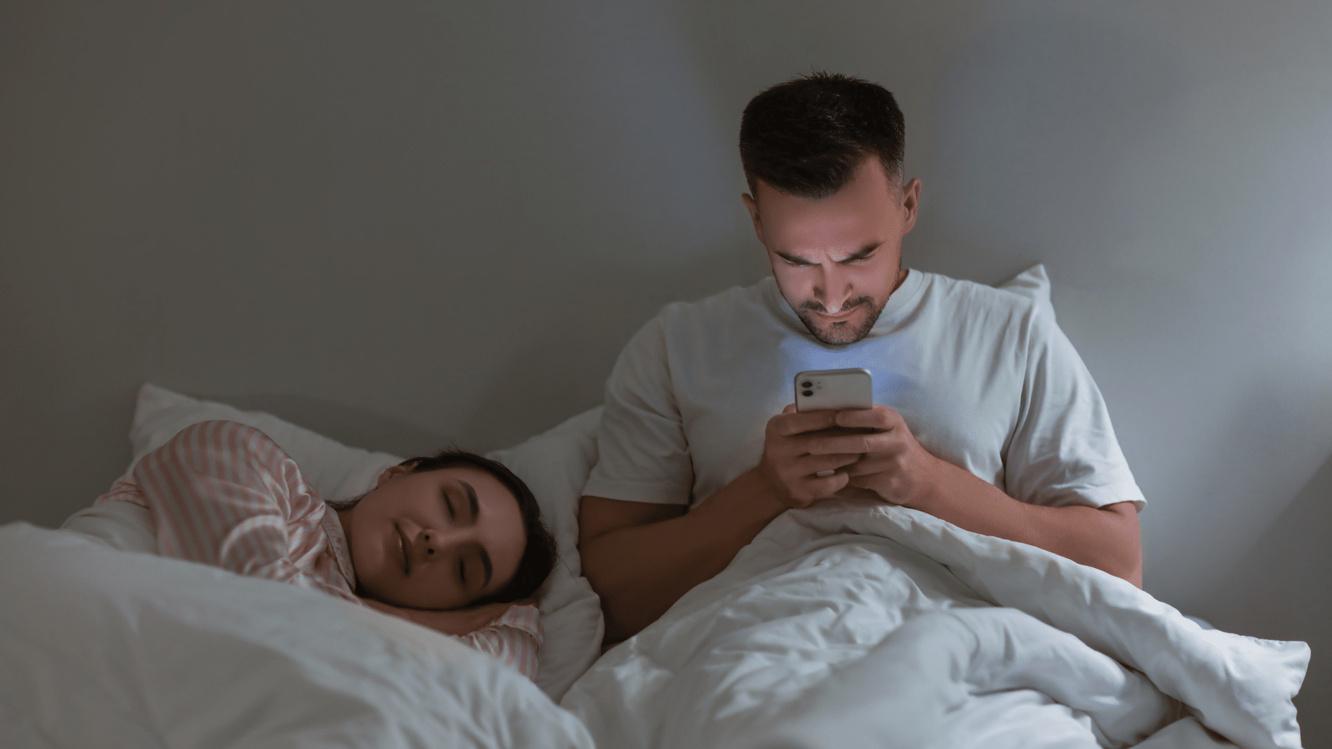 Naine ja mees voodis, mehel telefon käes kust paistab sinist valgust