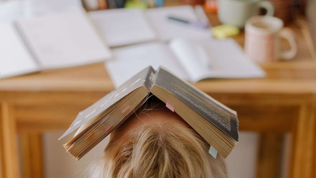 Naine istub ja tal on avatud raamat peas, stress